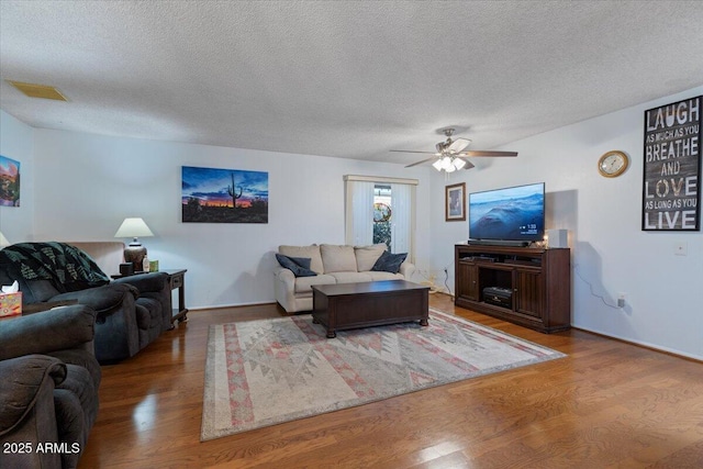 living room featuring hardwood / wood-style flooring, ceiling fan, and a textured ceiling