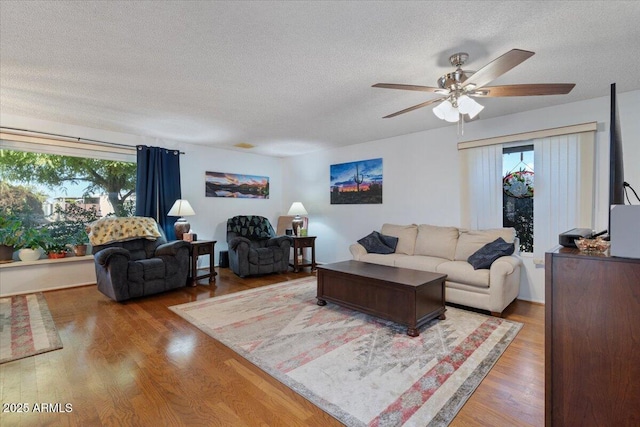 living room featuring ceiling fan, wood-type flooring, and a textured ceiling