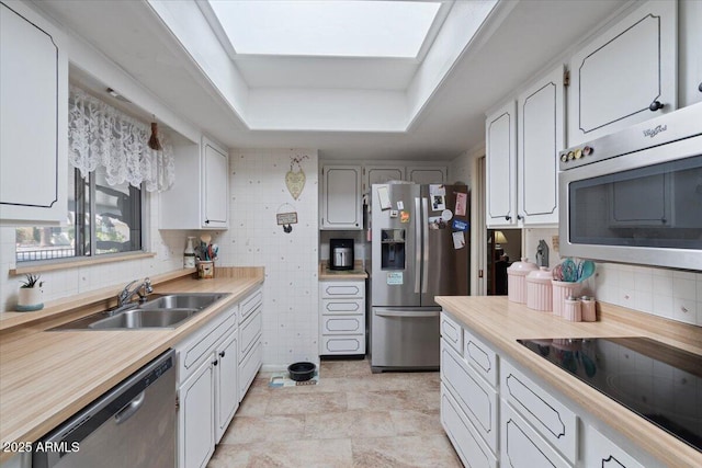 kitchen with sink, white cabinetry, backsplash, stainless steel appliances, and a tray ceiling