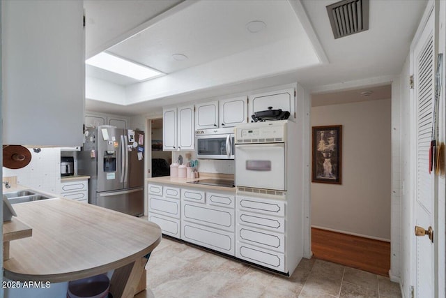 kitchen with tasteful backsplash, white cabinetry, appliances with stainless steel finishes, and a tray ceiling