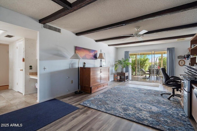 office space featuring beamed ceiling, ceiling fan, a textured ceiling, and light hardwood / wood-style flooring