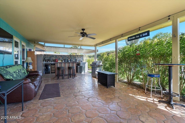 view of patio / terrace with area for grilling, ceiling fan, and a bar