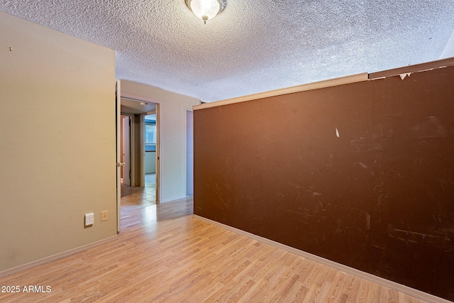 spare room featuring light hardwood / wood-style flooring and a textured ceiling