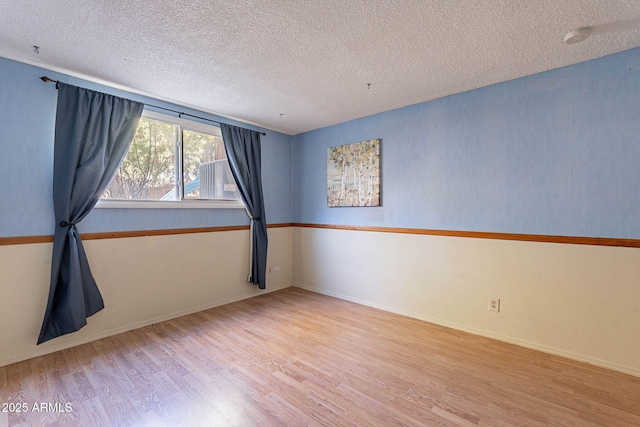 spare room featuring light hardwood / wood-style floors and a textured ceiling