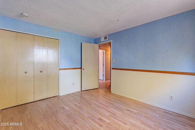 unfurnished bedroom featuring light hardwood / wood-style floors, a closet, and a textured ceiling