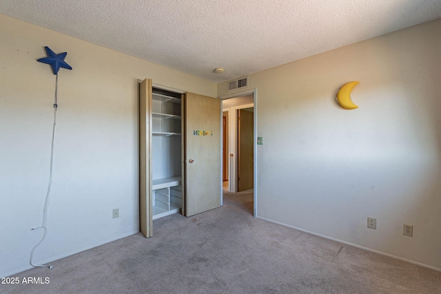 unfurnished bedroom featuring light colored carpet, a textured ceiling, and a closet