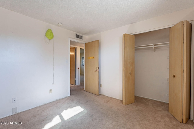 unfurnished bedroom featuring light carpet, a closet, and a textured ceiling