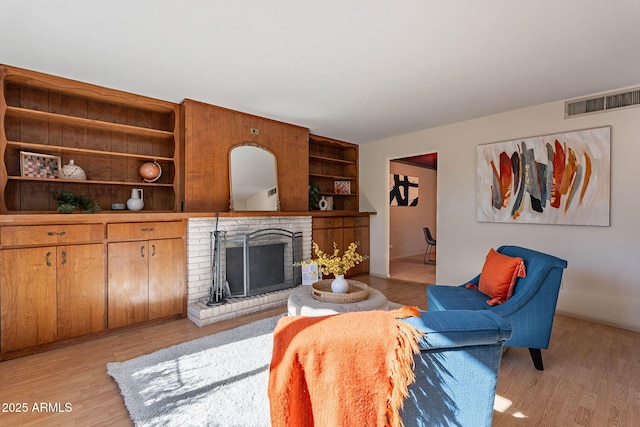 living room with light hardwood / wood-style floors and a brick fireplace