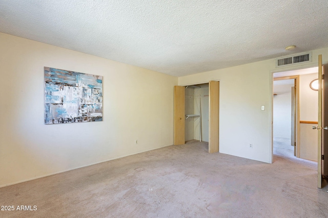 unfurnished bedroom with light colored carpet, a closet, and a textured ceiling