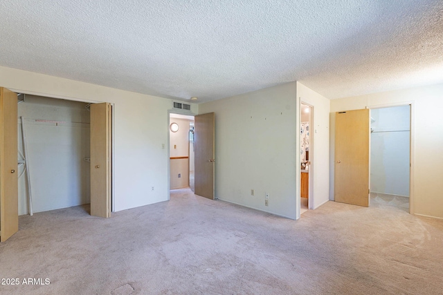 unfurnished bedroom with light colored carpet, a closet, and a textured ceiling