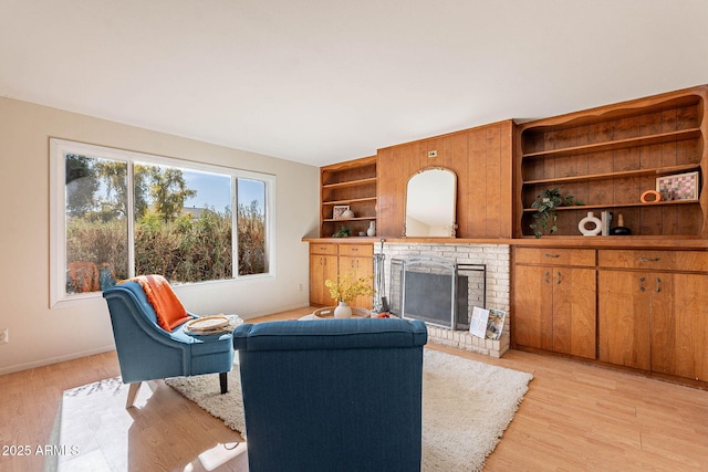 living room featuring a fireplace, built in features, and light wood-type flooring