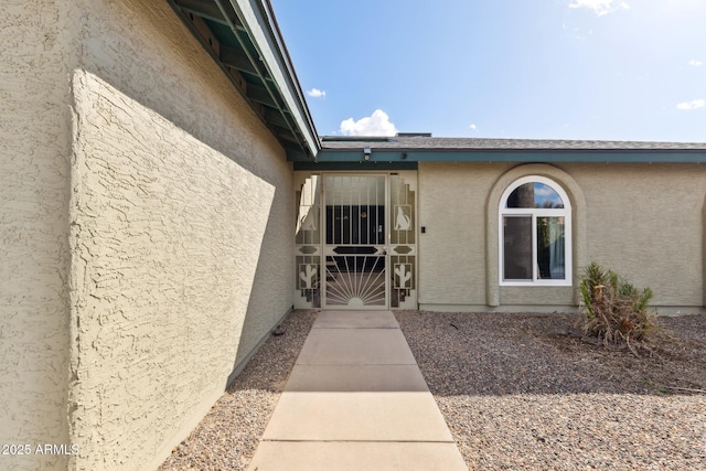 doorway to property with a gate and stucco siding