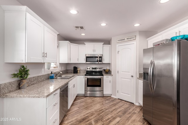 20750 E Chase Ct, Florence, AZ 85132 - kitchen featuring appliances with stainless steel finishes, light wood finished floors, white cabinetry, recessed lighting, and light stone counters