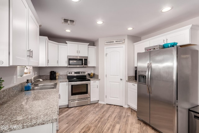 20750 E Chase Ct, Florence, AZ 85132 - kitchen featuring appliances with stainless steel finishes, white cabinets, light wood finished floors, and recessed lighting