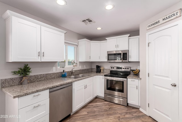 20750 E Chase Ct, Florence, AZ 85132 - kitchen with appliances with stainless steel finishes, white cabinetry, recessed lighting, and wood finished floors