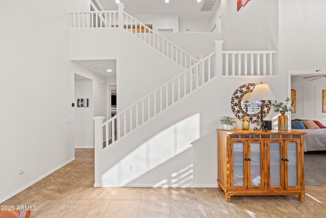 staircase with tile patterned flooring, a high ceiling, and ceiling fan