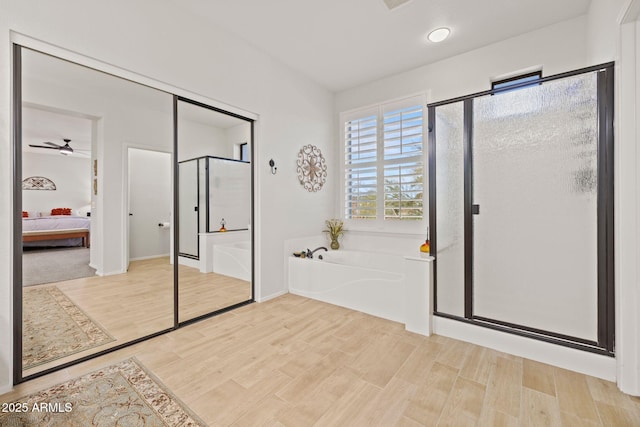 bathroom with hardwood / wood-style floors, ceiling fan, and shower with separate bathtub