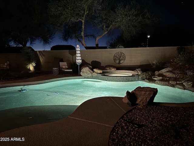 pool at night with an in ground hot tub