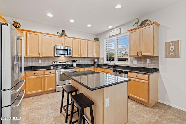 kitchen featuring a center island, sink, stainless steel appliances, dark stone counters, and a breakfast bar