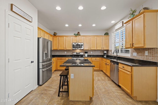 kitchen featuring appliances with stainless steel finishes, sink, light brown cabinets, a center island, and a breakfast bar area