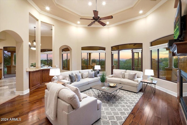 living room featuring dark hardwood / wood-style floors, a high ceiling, ornamental molding, and ceiling fan