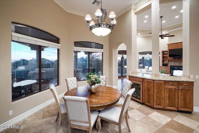 dining space featuring ceiling fan with notable chandelier, ornamental molding, and a high ceiling