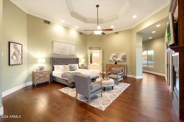 bedroom featuring dark wood-type flooring, ornamental molding, a tray ceiling, and ceiling fan