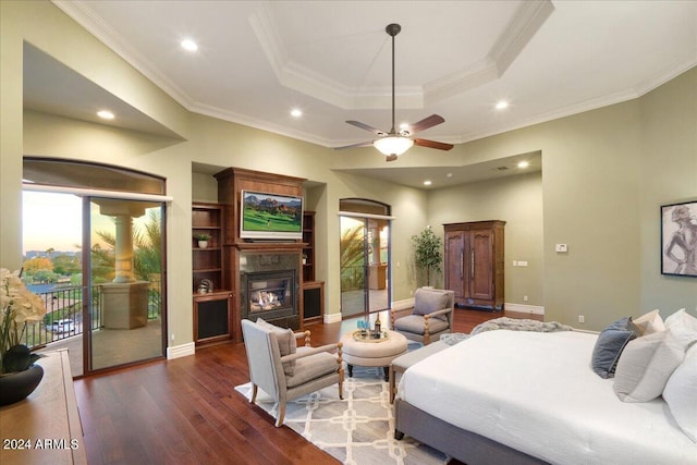 bedroom with ceiling fan, a raised ceiling, dark wood-type flooring, crown molding, and access to exterior