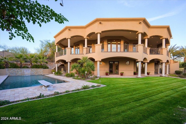 back of house featuring french doors, a balcony, a yard, and a patio