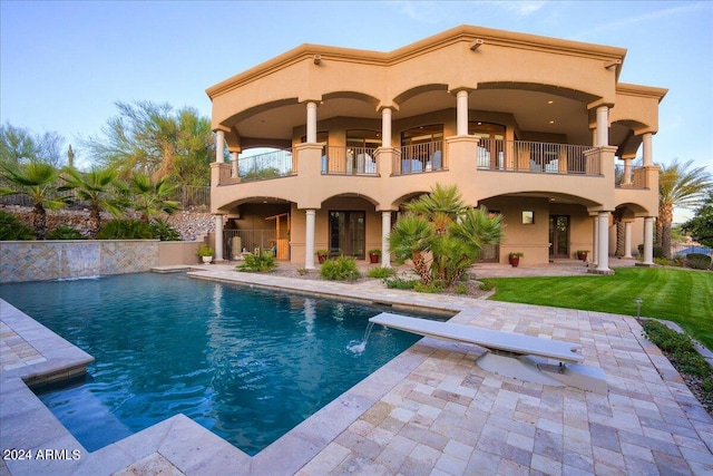 rear view of house featuring a lawn, pool water feature, a balcony, and a patio area