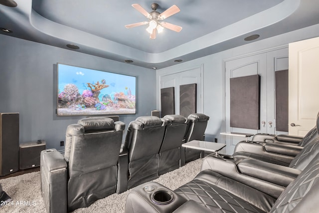 cinema room featuring a raised ceiling and ceiling fan