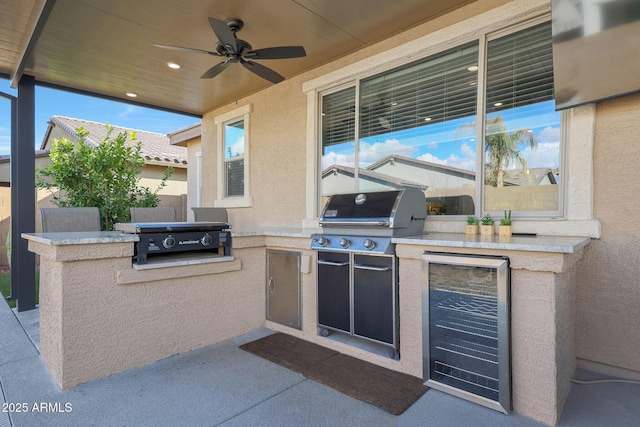 view of patio featuring area for grilling, beverage cooler, ceiling fan, and exterior kitchen