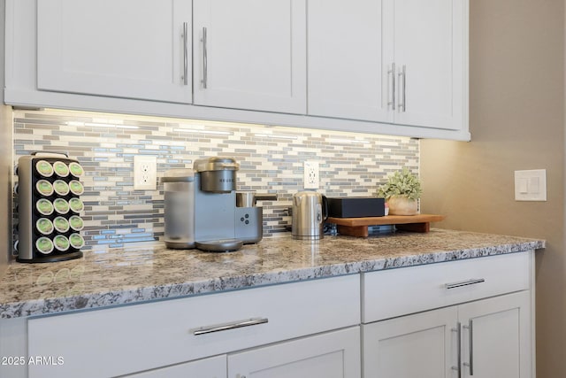 interior space featuring white cabinetry, light stone countertops, and decorative backsplash