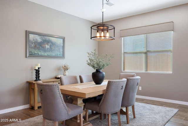 dining space with hardwood / wood-style floors and an inviting chandelier