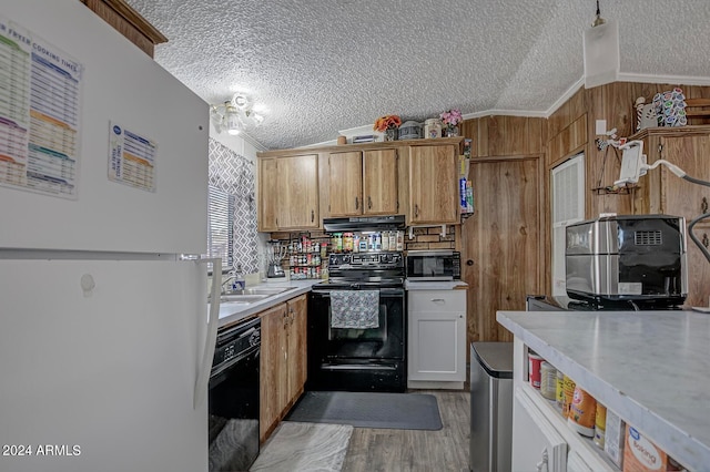 kitchen featuring a textured ceiling, light hardwood / wood-style floors, crown molding, black appliances, and vaulted ceiling