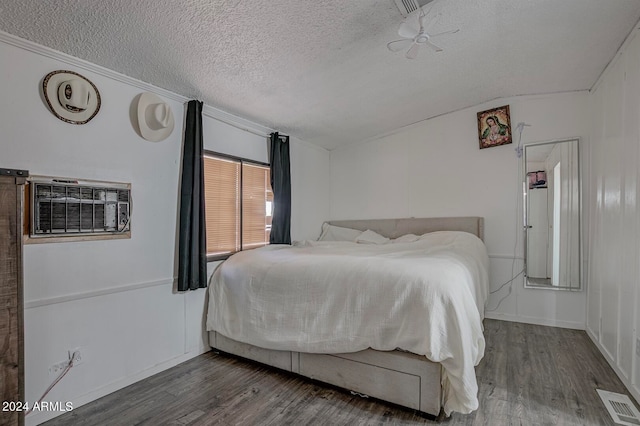 bedroom featuring a wall unit AC, dark hardwood / wood-style floors, and a textured ceiling