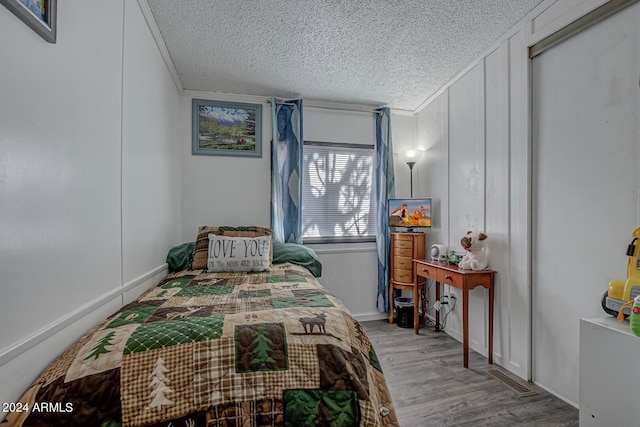 bedroom featuring ornamental molding, light hardwood / wood-style flooring, and a textured ceiling