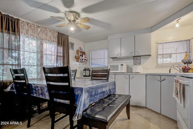 interior space with light stone countertops, white appliances, ceiling fan, white cabinets, and light tile floors