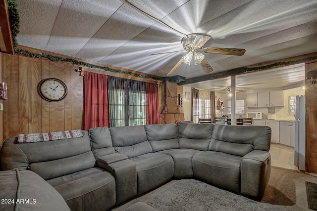 carpeted living room featuring wood walls and ceiling fan