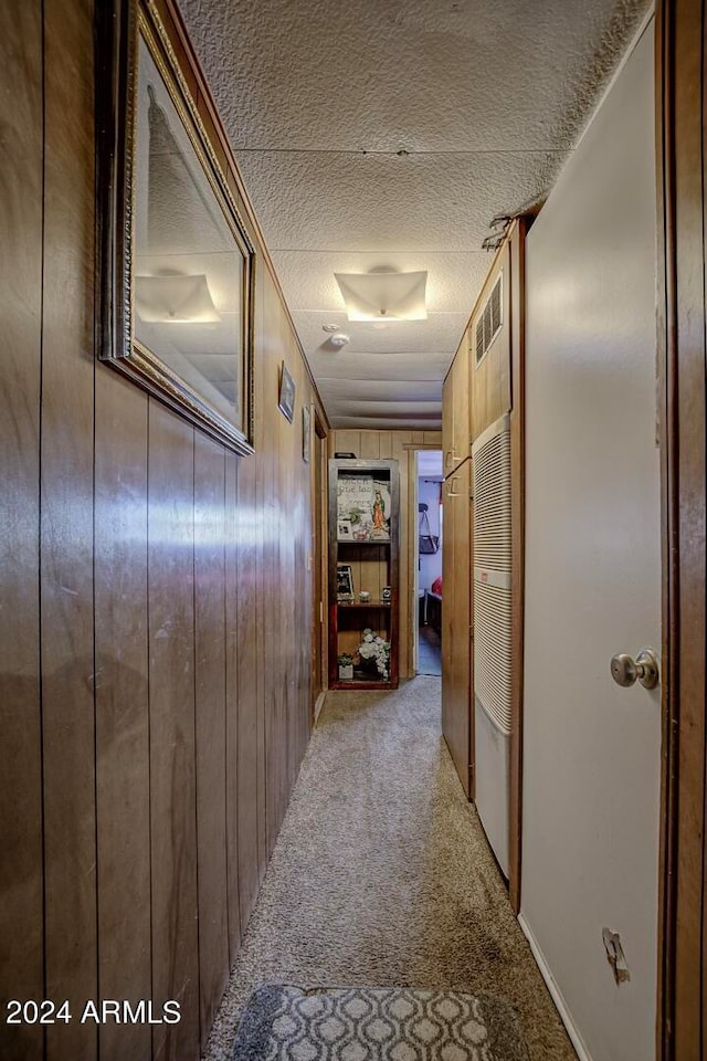 hallway with wood walls and light carpet