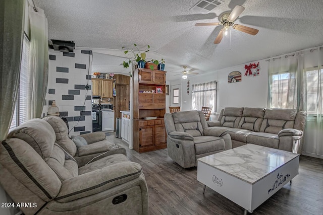 living room featuring dark hardwood / wood-style floors, ceiling fan, and a textured ceiling