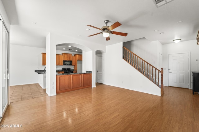 2337 E Fraktur Rd, Phoenix, AZ 85040 - unfurnished living room with light wood-style floors, arched walkways, a ceiling fan, and visible vents