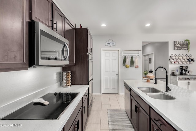 kitchen with dark brown cabinets, stainless steel appliances, a sink, and light countertops