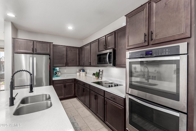 kitchen featuring stainless steel appliances, a sink, light countertops, and dark brown cabinetry