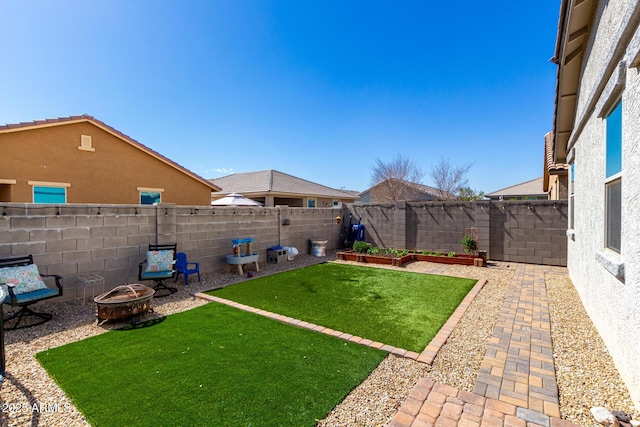 view of yard featuring an outdoor fire pit, a fenced backyard, and a garden