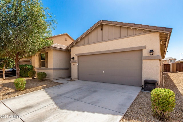 view of front of house with a tile roof, stucco siding, an attached garage, fence, and driveway