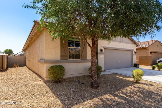 view of front of property featuring an attached garage, fence, a tile roof, driveway, and stucco siding