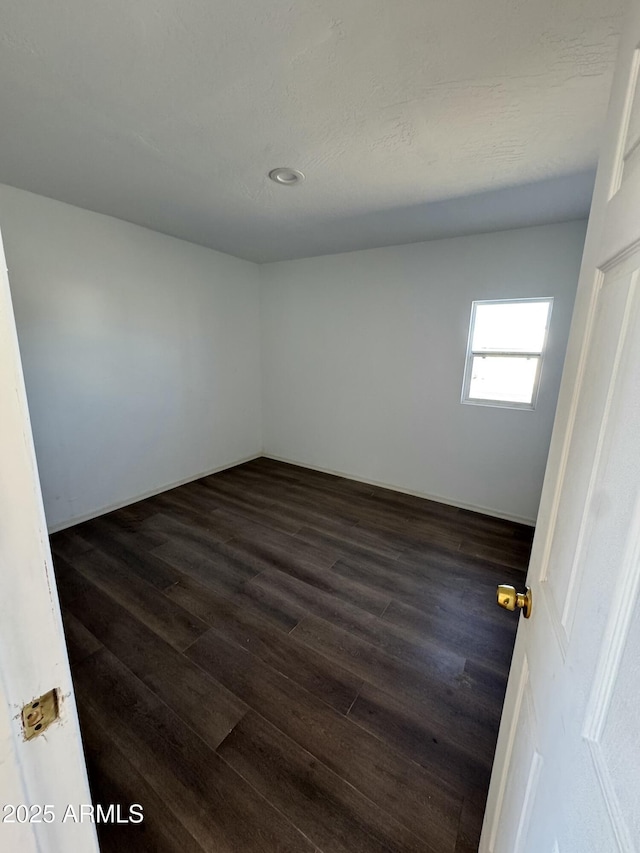 empty room with dark hardwood / wood-style flooring