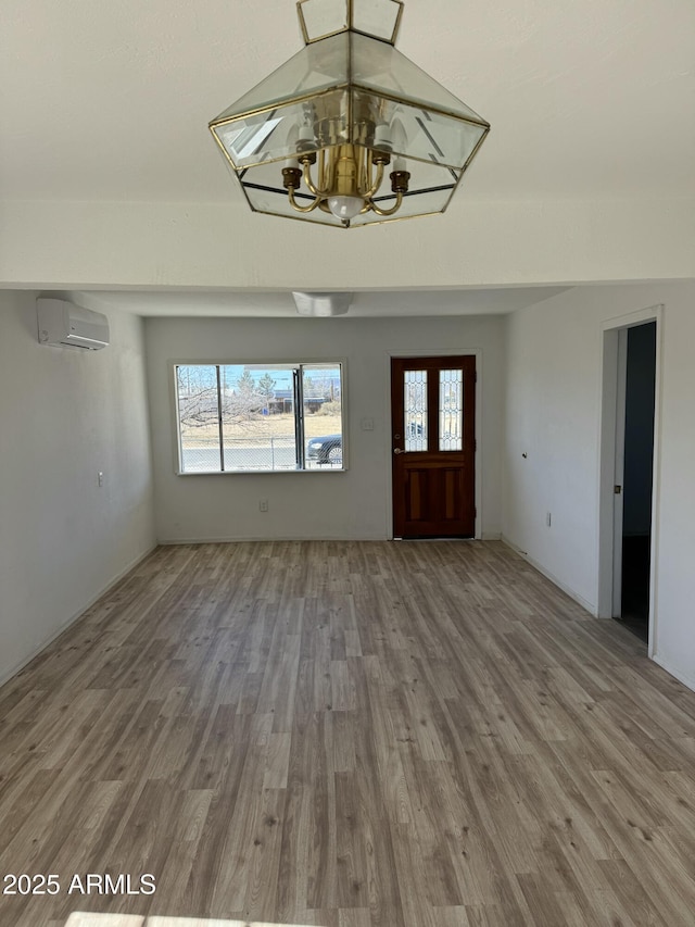 entrance foyer featuring hardwood / wood-style floors, a wall mounted air conditioner, and an inviting chandelier