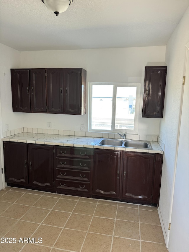 kitchen featuring sink, light tile patterned floors, and dark brown cabinetry